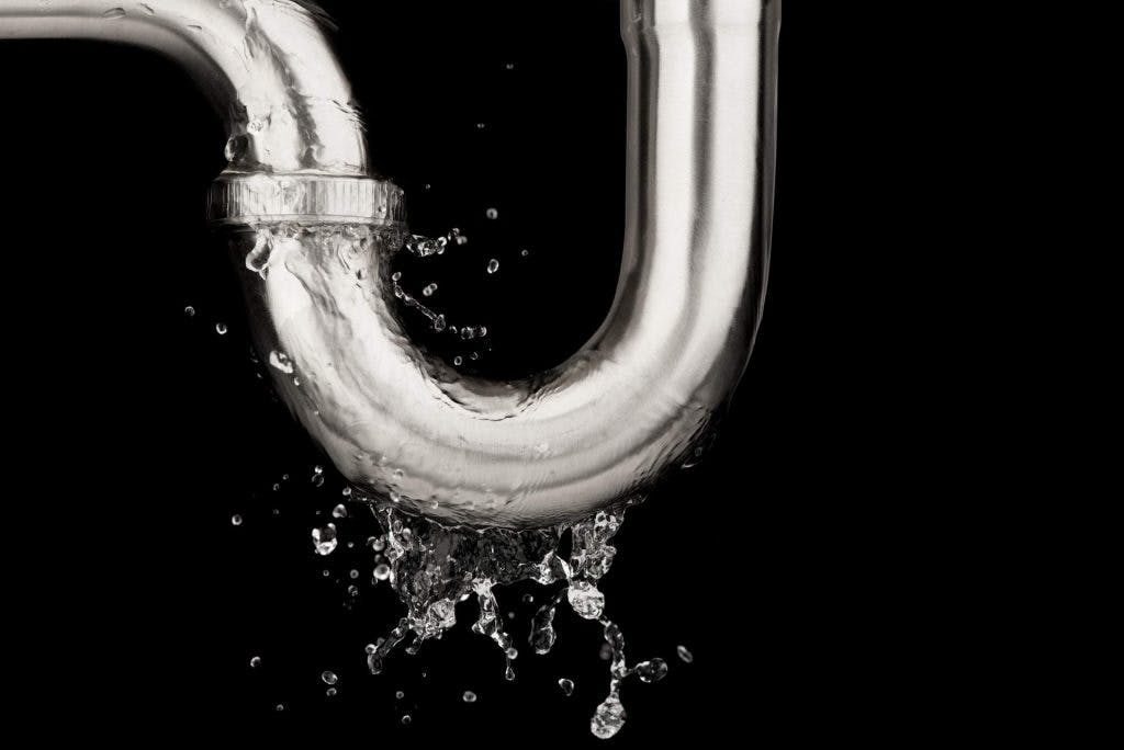 leaking-water-from-stainless-steel-sink-pipe-isolated-black-background