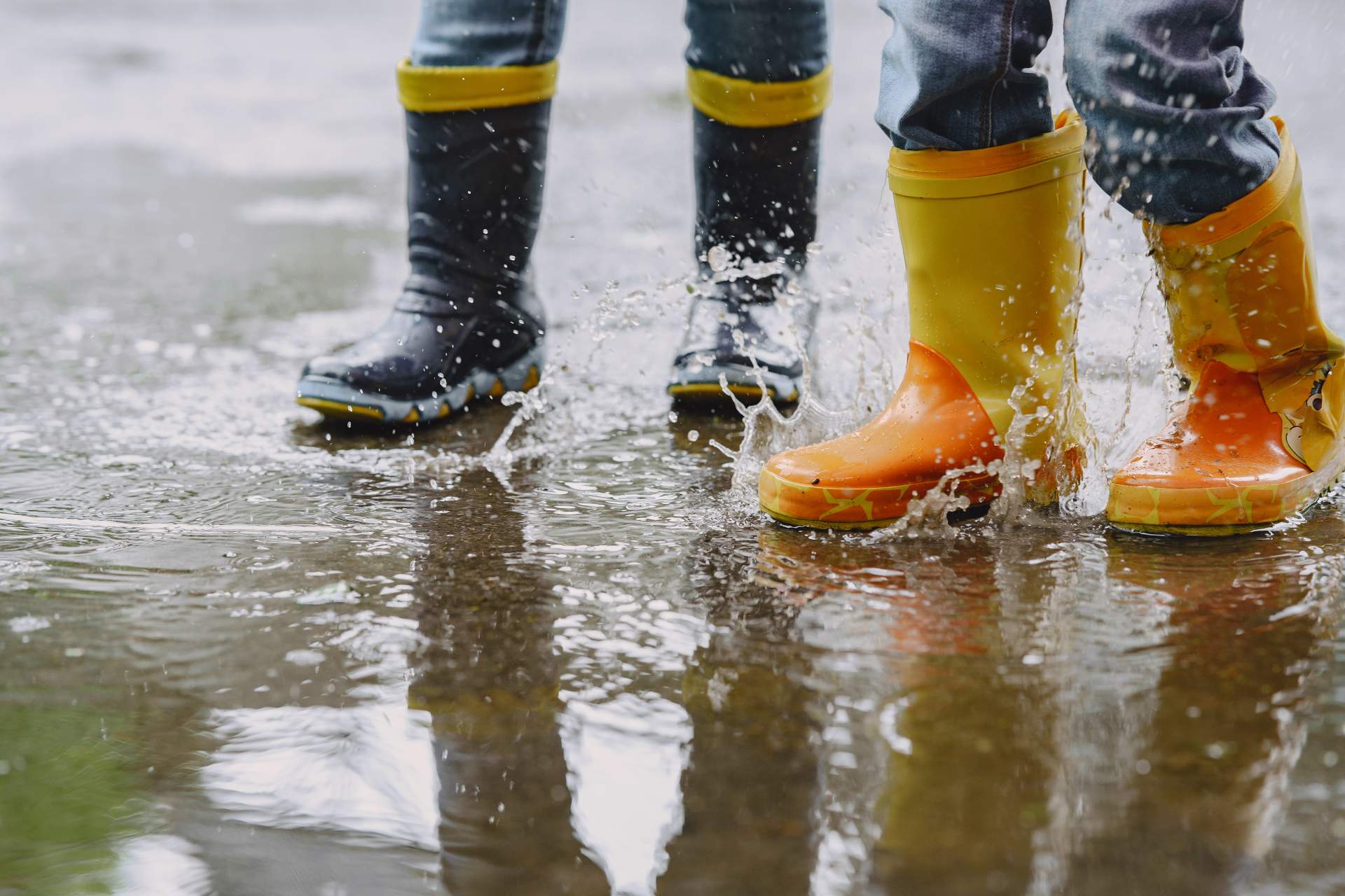 funny-kids-rain-boots-playing-with-paper-ship-by-puddle